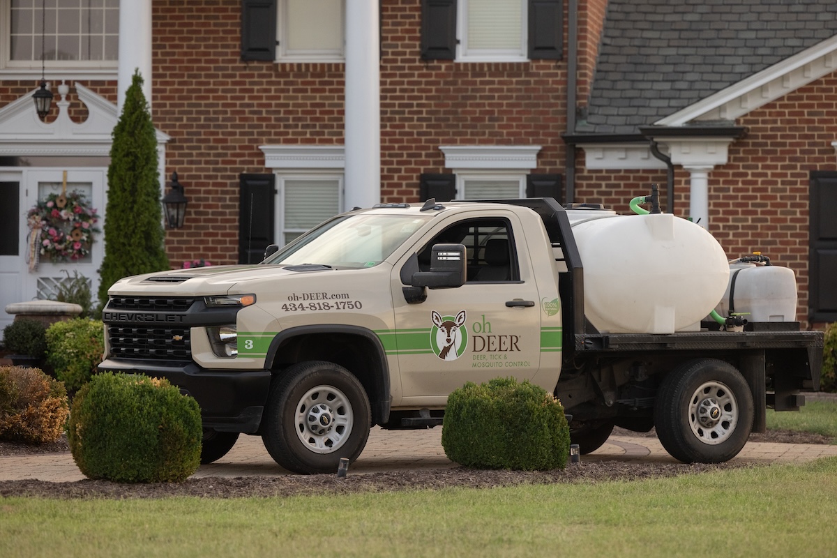 An oh DEER pest control truck with spray tanks is parked on a driveway in front