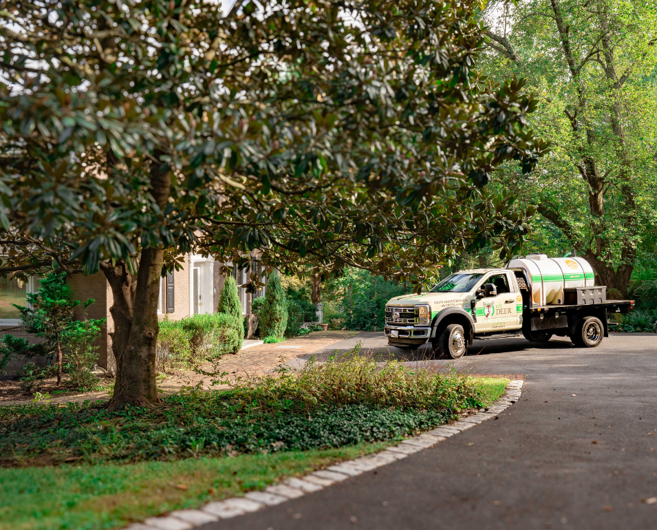 An 'Oh Deer' deer repellent service truck is parked on a residential driveway in front