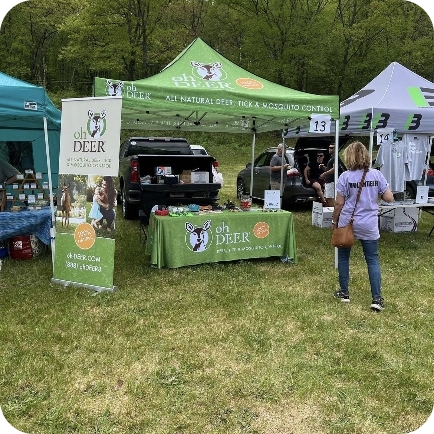 ohDEER vendor booth setup outdoors with green tents, banners, and product displays.