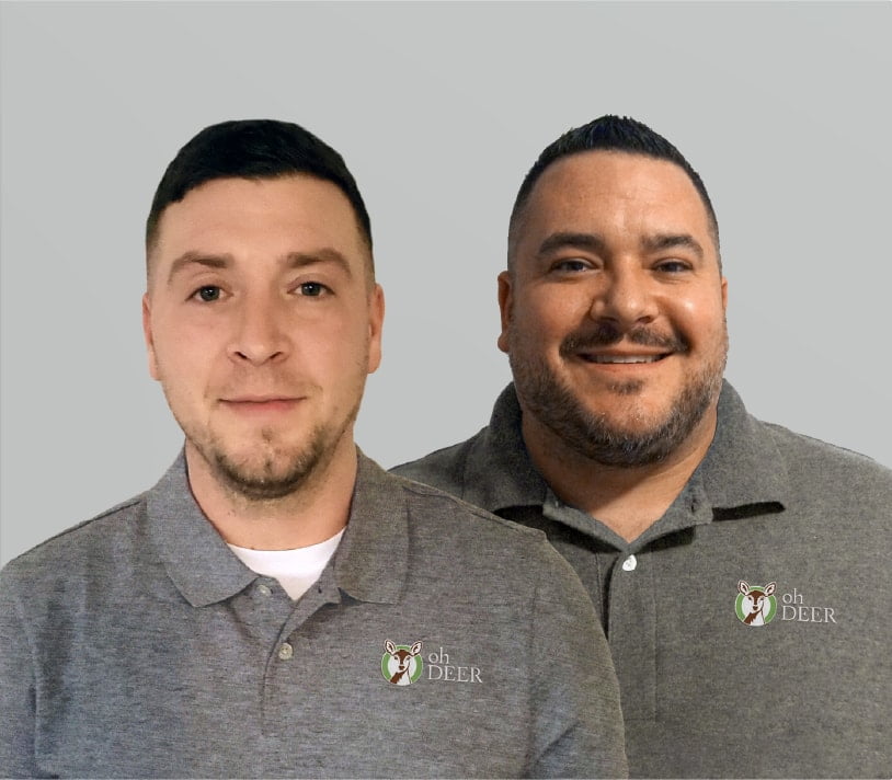 Two men in grey 'oh DEER' polo shirts smile against a simple grey background