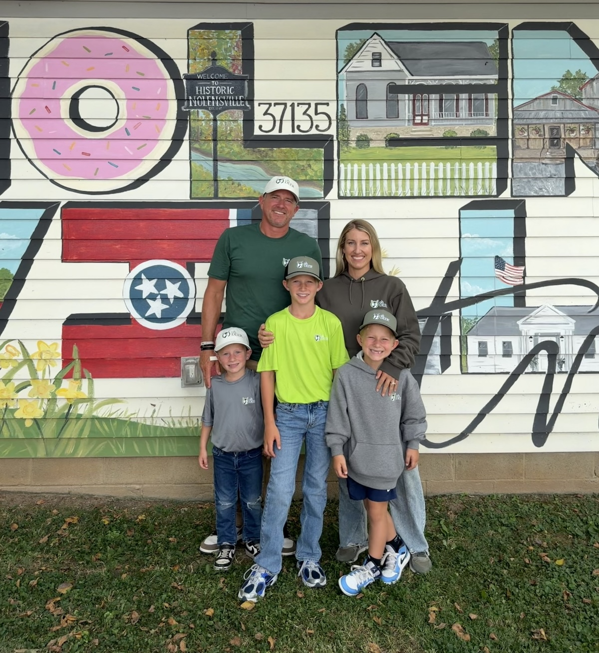 A smiling family of five stands in front of a vibrant