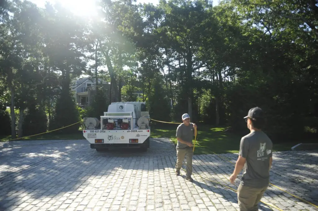 Two Oh-Deer technicians deploy a hose from their pest control truck on a sunny