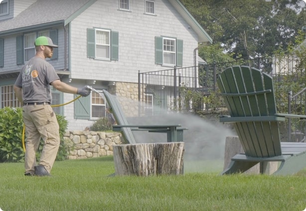 An ohDEER employee spraying a backyard with mosquito and tick spray as people learn more about us.
