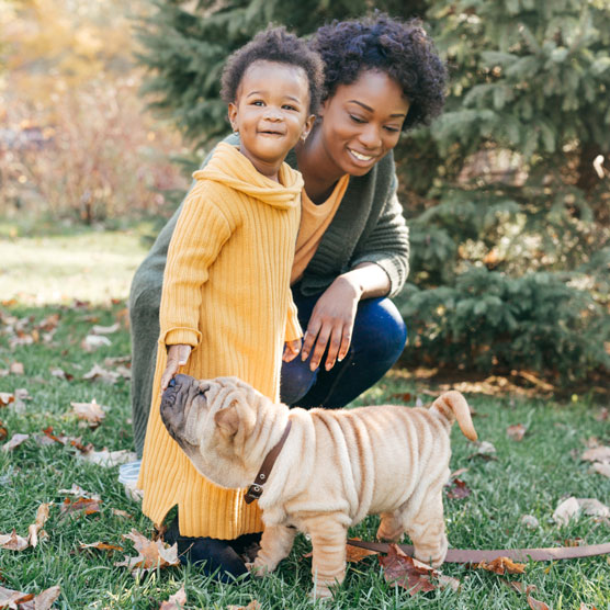 Diverse lady and her daughter and dog enjoying their outdoor space.
