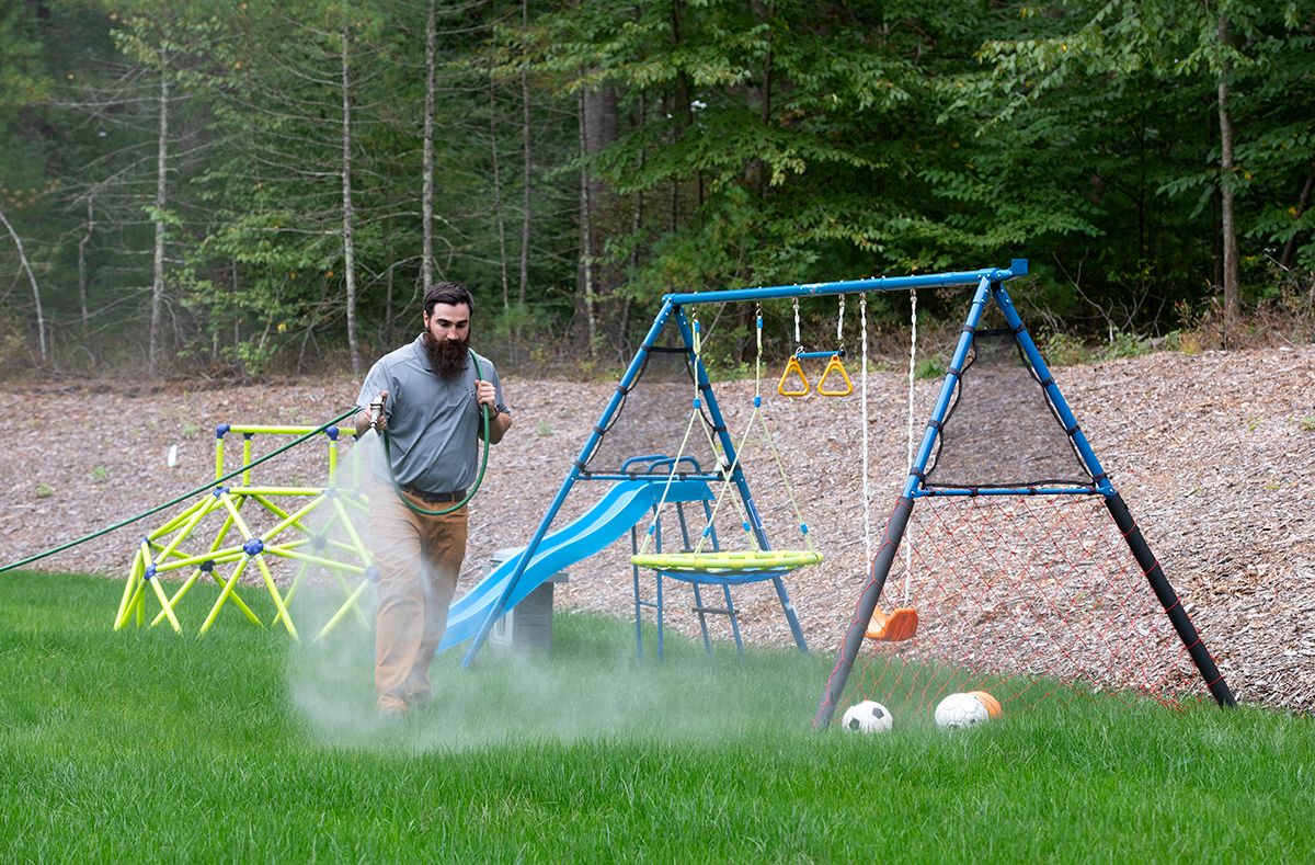 ohDEER employee spraying the play yard of a client with their all natural mosquito and tick control spray.