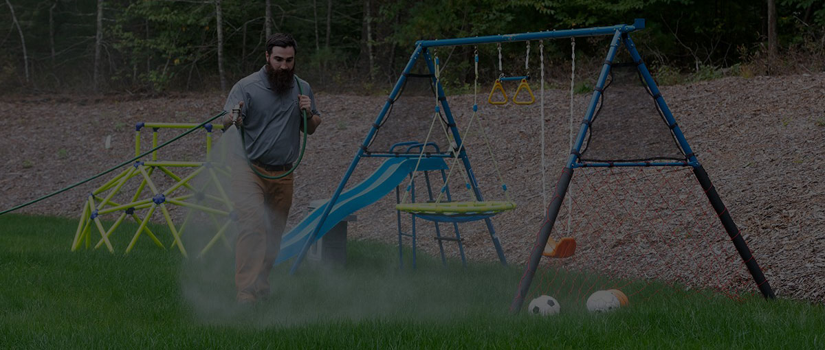 An ohDEER employee spraying a playground with tick control spray.