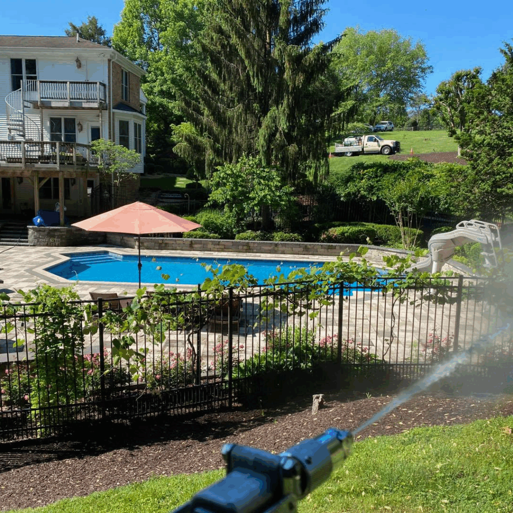 spraying all-natural tick & mosquito control by a pool 